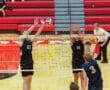 High school volleyball match at Peters Township, players block a spike at the net, showcasing competitive spirit and teamwork.