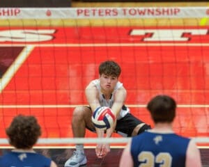 High school volleyball player sets up for a serve during a game at Peters Township, showcasing athletic focus and teamwork.