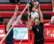 Player prepares to set a volleyball during a competitive match, with the opposing player attempting to block.