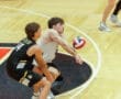 Two male volleyball players engaged in a game, one receiving a serve on the court.