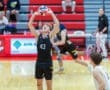 A young male volleyball player prepares to set the ball during a competitive match in a gymnasium.