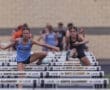 Two female athletes competing in a hurdle race, showcasing determination and athleticism on the track.