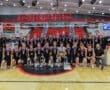 Boys volleyball team celebrating their championship win with medals and trophy on the court at Peters Township.