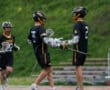 Lacrosse players celebrating on the field, showcasing teamwork and sportsmanship in a dynamic game setting.