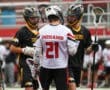 Lacrosse players in team jerseys discussing strategy during a game on the field, showcasing teamwork and athletic spirit.