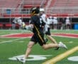 Lacrosse player in black jersey sprinting on the field, showcasing athletic movement during a game.