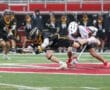 Two lacrosse players compete intensely for possession of the ball on a rainy field, showcasing athleticism and teamwork.