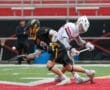 Two youth lacrosse players compete for possession of the ball on a field, showcasing athletic movement and teamwork.