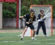 High school lacrosse players in action on a field, focused on a game during rainy weather.