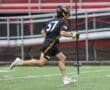 Lacrosse player in action, wearing uniform #37, sprinting on the field during a game in rainy weather.