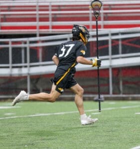 Lacrosse player in action, wearing uniform #37, sprinting on the field during a game in rainy weather.