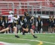 High school lacrosse players compete during a match, showcasing athletic moves and teamwork on a rainy day.