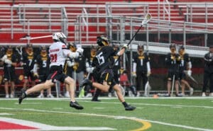 High school lacrosse players compete during a match, showcasing athletic moves and teamwork on a rainy day.