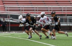 High school lacrosse players sprint across the field, competing fiercely during a game.