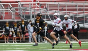 Players in lacrosse uniforms compete on the field, showcasing athleticism and teamwork during an intense match.
