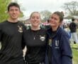 Three young rowers smile together at a rowing event, showcasing camaraderie and team spirit in their athletic gear.