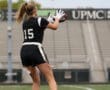 Female football player wearing jersey #15 catches a pass on a field, showcasing her agility and skill in action.