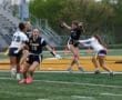 Exciting moment in girls' flag football game, player leaps to catch a pass while being defended by an opponent.
