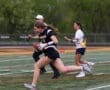 Female athlete running with a football during a flag football game, showcasing agility and teamwork on the field.