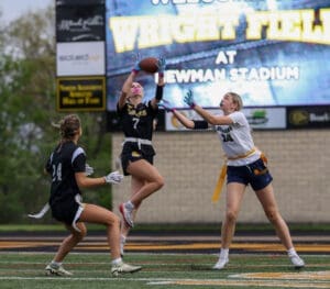 Exciting action shot of female athletes in a flag football game at Newman Stadium, capturing a key interception play.