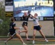 Two female athletes compete for a football during a game at Wright Field, Newnan Stadium, showcasing teamwork and skill.