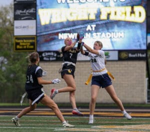 Two female athletes compete for a football during a game at Wright Field, Newnan Stadium, showcasing teamwork and skill.