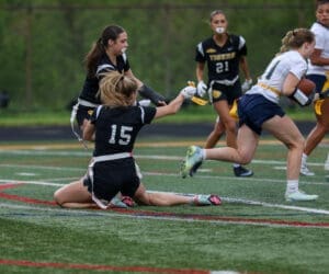 A dynamic moment in a girls' flag football game, showcasing teamwork and athleticism on an outdoor field.
