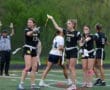 High school girls' flag football team in action, signaling plays on the field during a game.