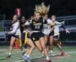 Girls' flag football game: player #20 from the Tigers dodges opponents while running with the ball under stadium lights.