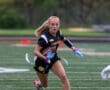 Girl in black Tigers uniform running with a football on a field, showcasing athleticism and focus during a game.