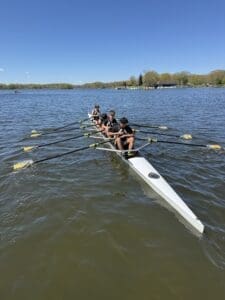 Rowing team practicing on a sunny day, showcasing teamwork and athleticism on a calm lake.