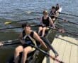 Rowing team preparing to launch on a sunny day, showcasing teamwork on the water with their oars ready.
