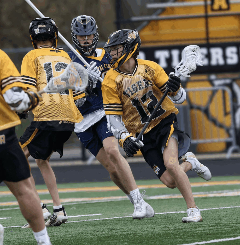 High school lacrosse players in action, competing on the field with excitement and teamwork during a match.