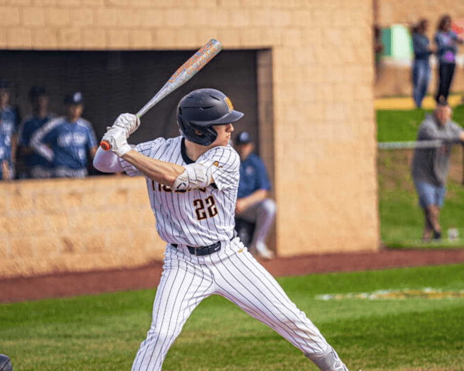Baseball player in a pinstripe uniform prepares to swing a bat during a game, with spectators in the background.