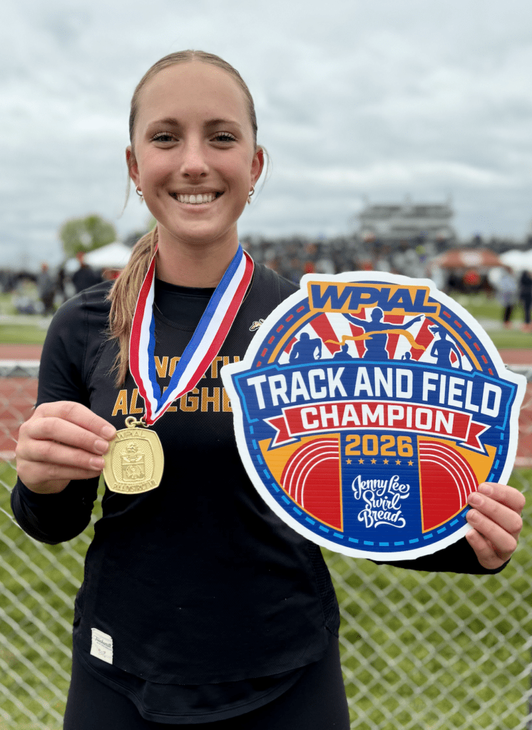 Young athlete holding a gold medal and champion plaque at the WPIAL Track and Field Championships, smiling proudly.
