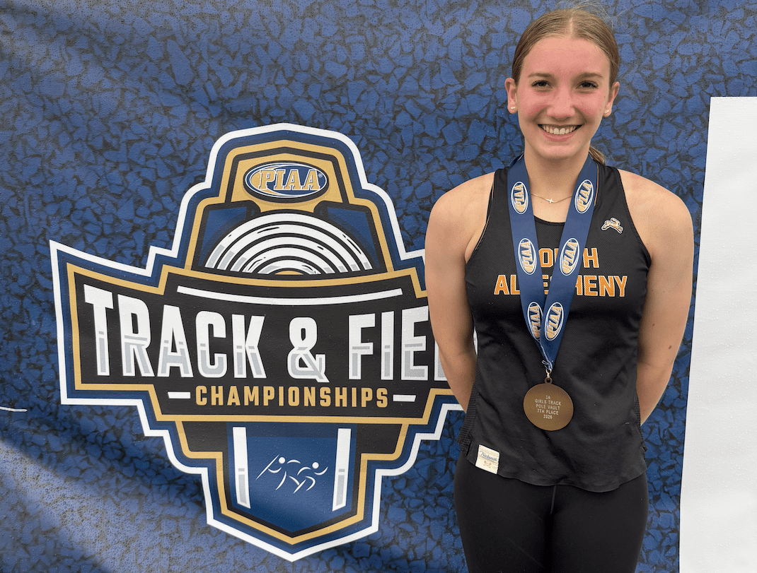 High school athlete proudly displaying a medal at the PIAA Track and Field Championships, showcasing her achievement.