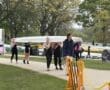Team of young women carrying a rowing shell at a lakeside boathouse during a spring rowing event.