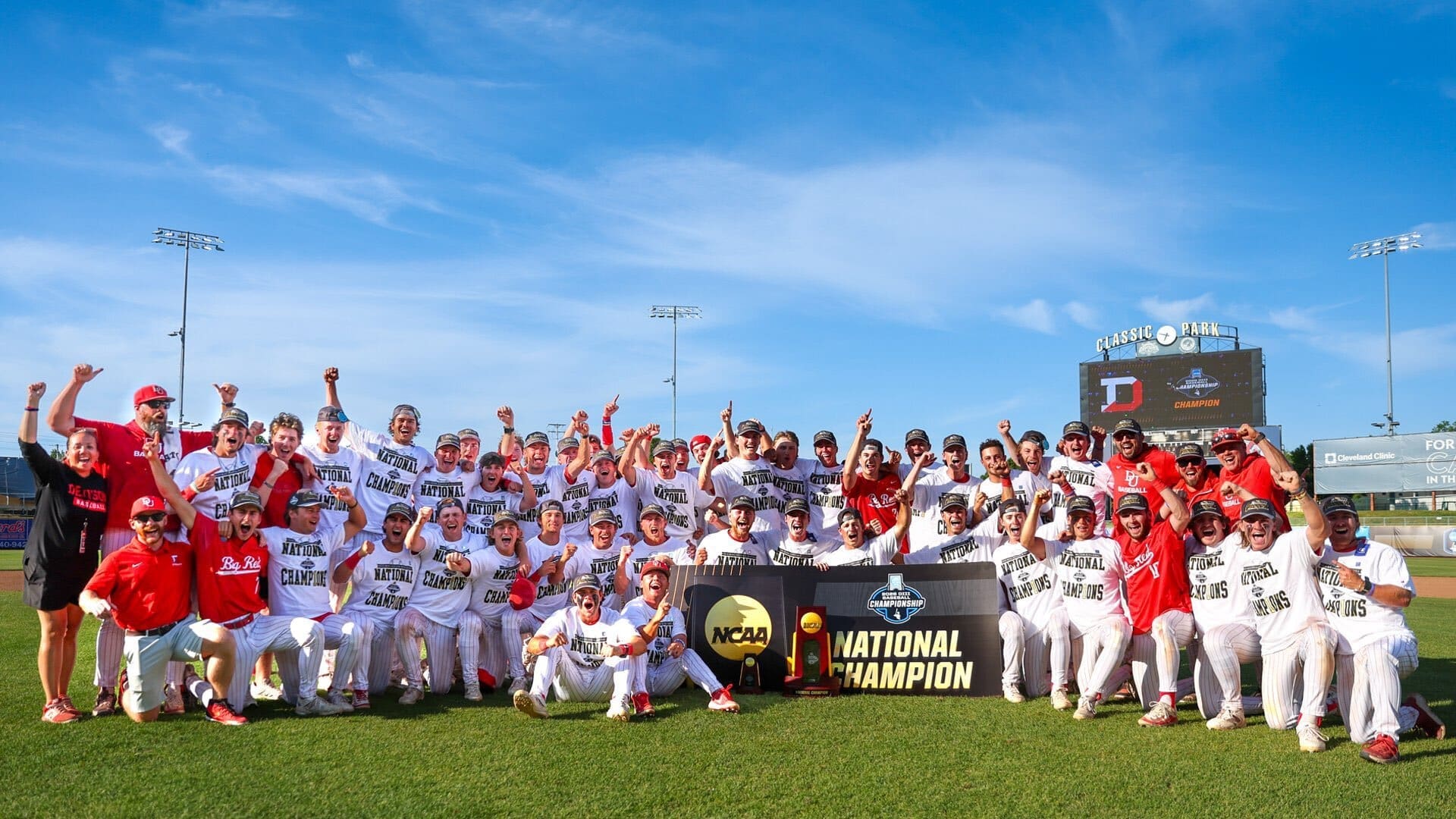 Team celebrating their NCAA National Championship victory, posing with a trophy at Classic Park, showcasing excitement and teamwork.