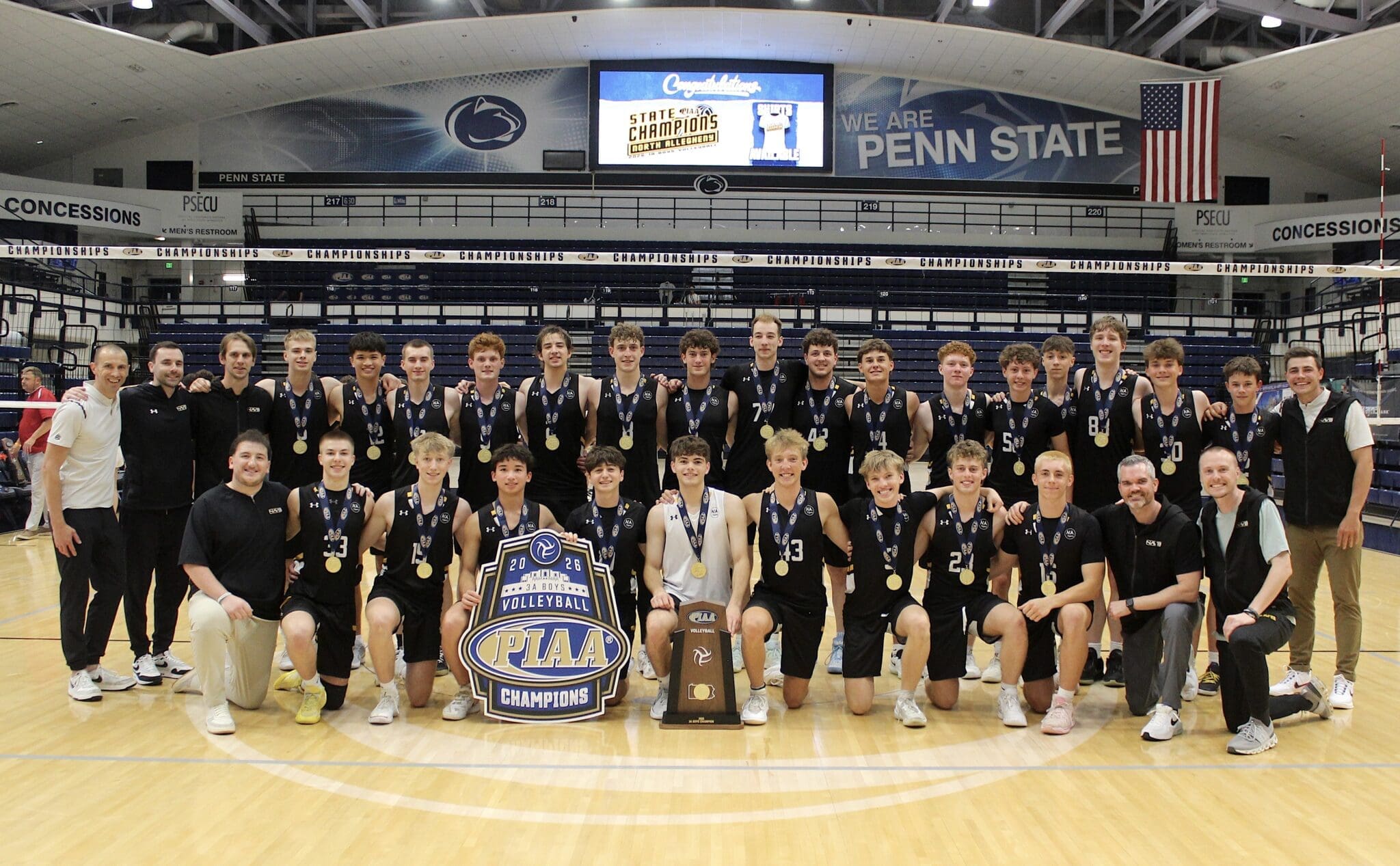 North Allegheny boys' volleyball team celebrating their PIAA championship victory at Penn State, wearing medals and holding trophies.