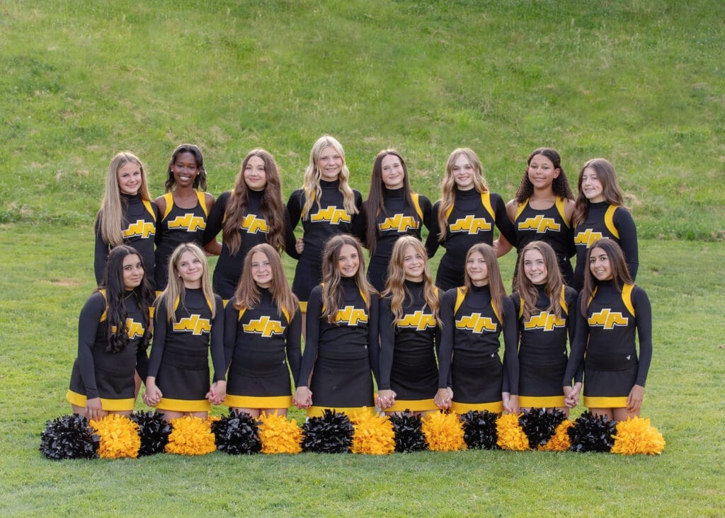 Cheerleading squad posing outdoors, wearing matching uniforms with pom-poms, showcasing team spirit and camaraderie.