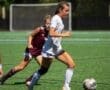 Young female soccer players compete on the field, with one sprinting towards the ball during an intense match.