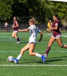 Two female soccer players competing on a field during a match, showcasing athleticism and teamwork.