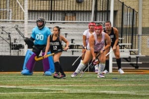High school field hockey players in action, featuring a goalie and team members ready for a play on the turf.