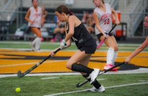 Field hockey players in action during a game, showcasing teamwork and skill on the turf.