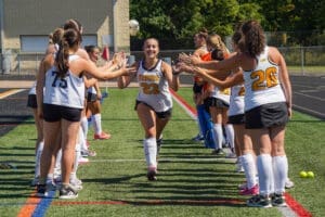 Field hockey team celebrates player number 23 during a game, creating an exciting and energetic atmosphere.