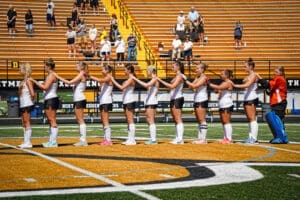 Field hockey team lined up before a match, showcasing team spirit on a sunny day at the stadium.