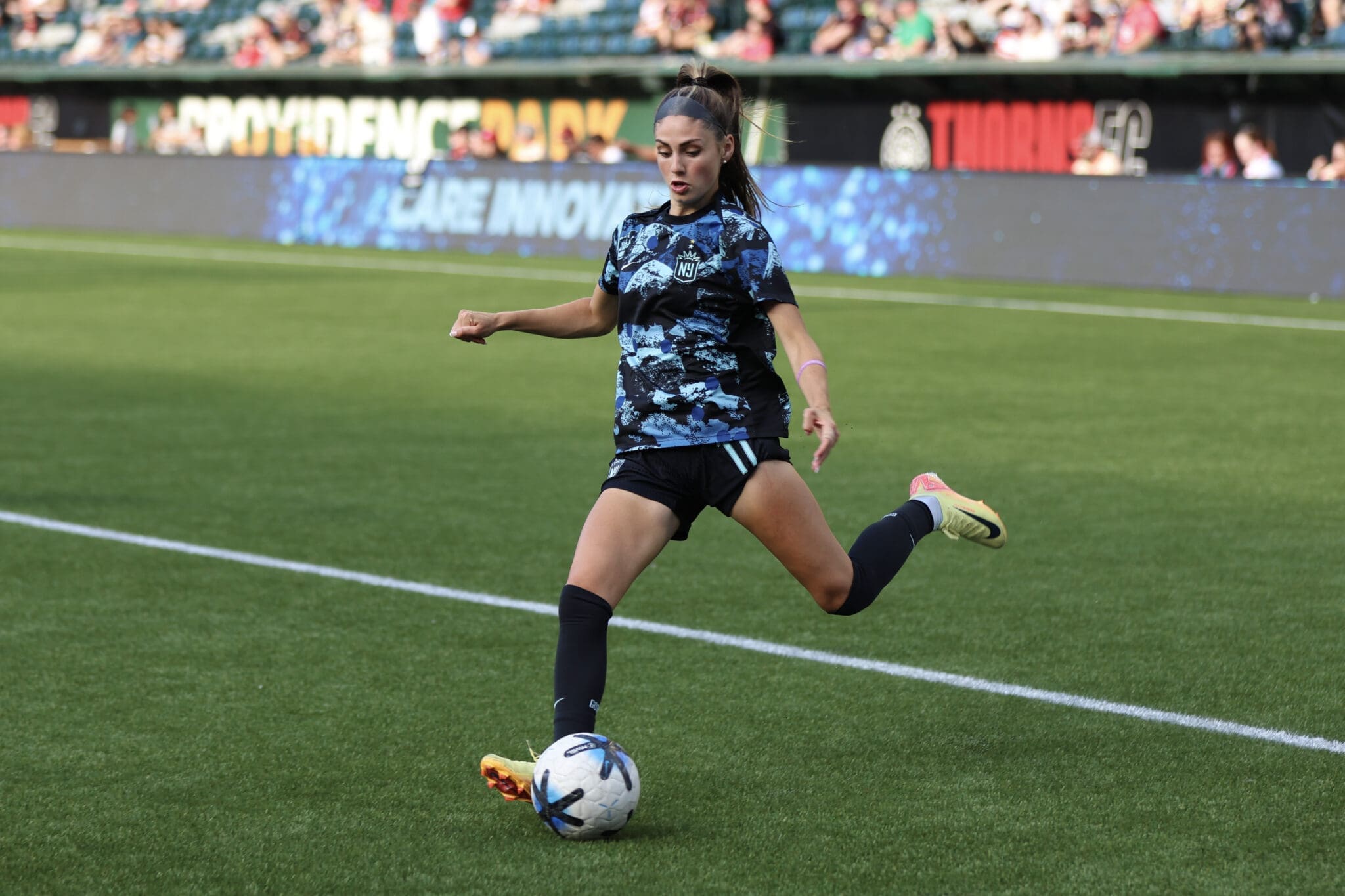 Female soccer player in action, striking a ball on a vibrant green field during a competitive match.