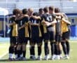 Soccer team huddling together for motivation before a match on the field. Team spirit and camaraderie on display.