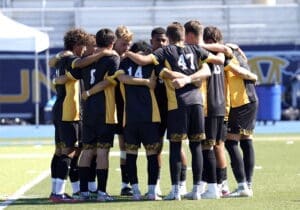 Soccer team huddling together for motivation before a match on the field. Team spirit and camaraderie on display.
