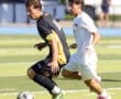 High school soccer players compete for the ball on the field, showcasing athleticism and teamwork during a match.